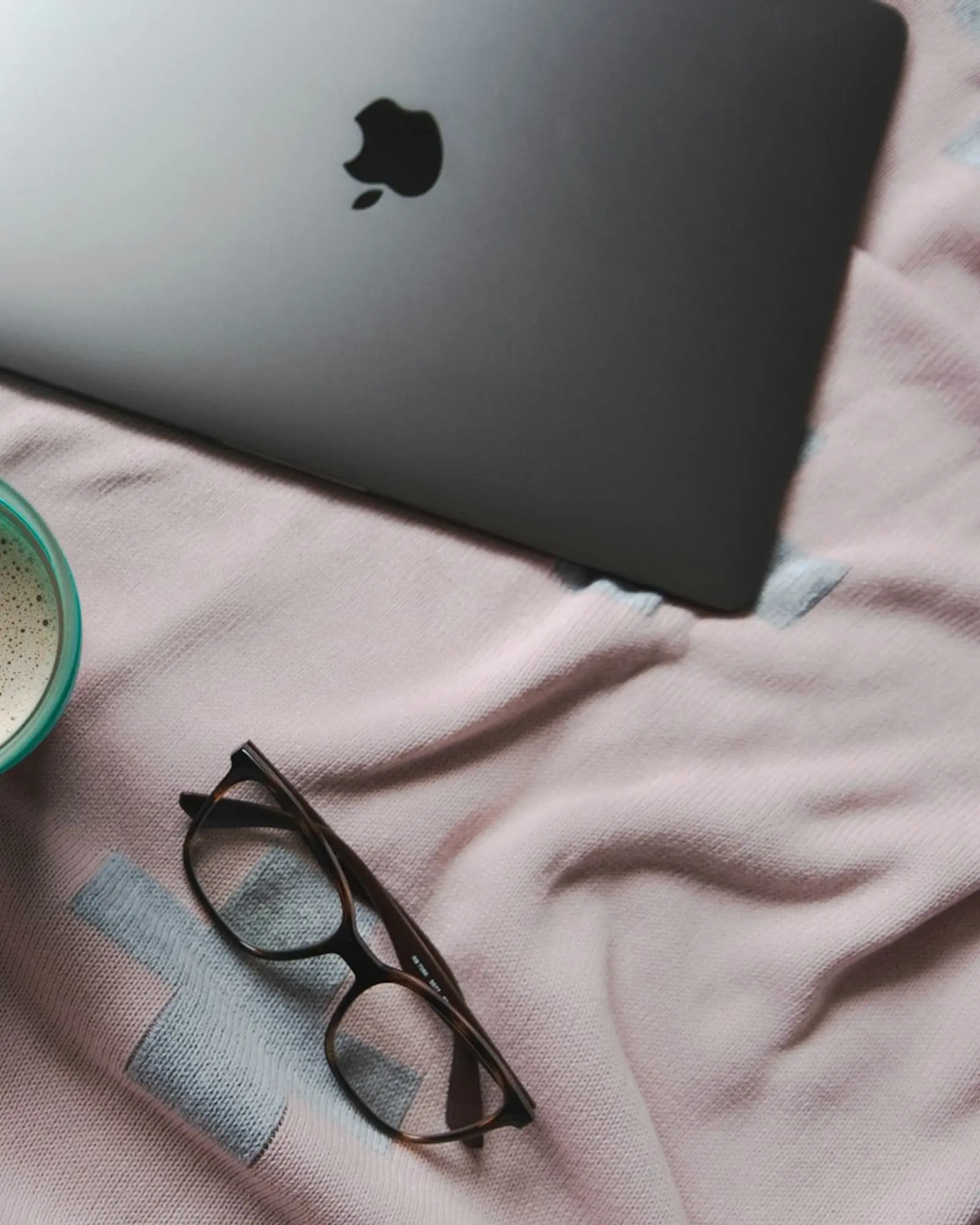 Le bureau de Camille : un ordinateur portable, des lunettes, un carnet.